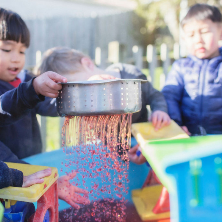 Toddlers with messy play and water play outdoors 