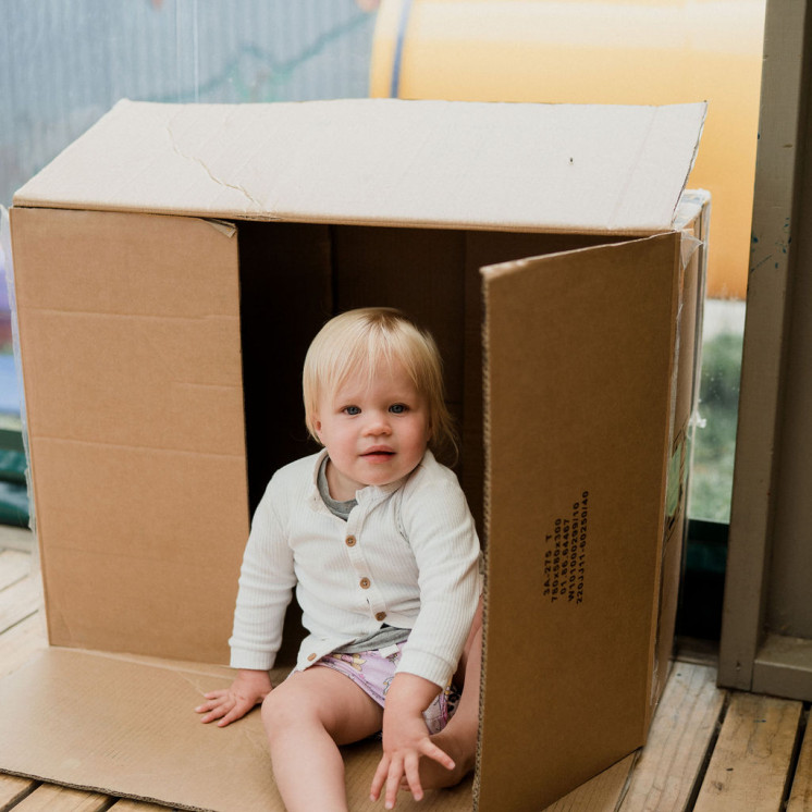Young baby playing peek a boo with a box at Busy Bees Frimley