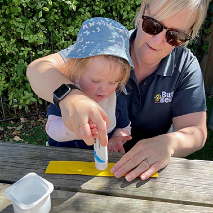 baby and teacher doing arts and craft at Busy Bees Southbrook